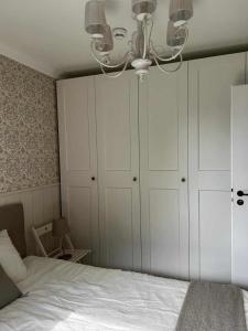 斯诺科Apartament nad Zegrzem 206 Luksus的一间卧室配有一张带白色橱柜和吊灯的床。