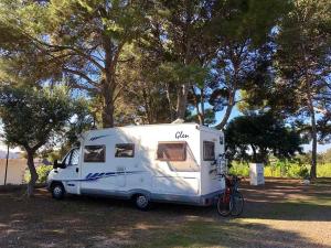 坎布里尔斯Camping Cambrils Caban的一辆白色大篷车停在树边的田野里
