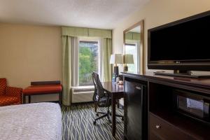 哥伦比亚Hampton Inn Columbia I-26/Harbison Blvd的酒店客房配有一张床和一张书桌及一台电视