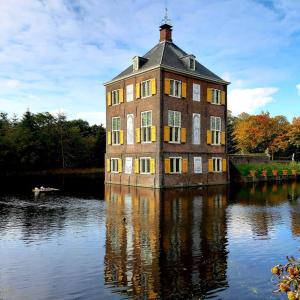 沃尔堡Koetshuis aan het water 3 bedroom villa的湖中一座大型砖砌建筑
