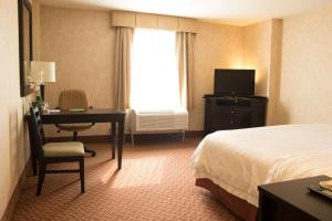 维多利亚城维多利亚城希尔顿汉普顿酒店的酒店客房配有一张床、一张书桌和一台电视。