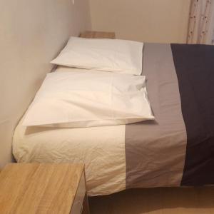 穆捷Djo的一张带白色床单和枕头的床,旁边是桌子