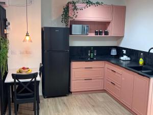 萨法德הצימר של אביטל的厨房配有粉色橱柜和黑色冰箱