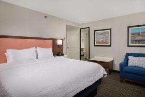 费尔法克斯费尔法克斯市汉普顿旅馆的酒店客房,配有一张床和一张蓝色椅子