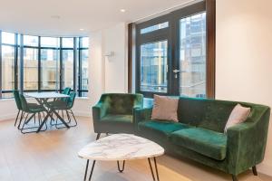 布伦特福德Brentford Apartments by Charles Hope的客厅配有绿色沙发和桌子