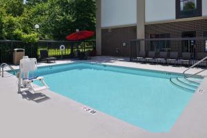 McLeansville格林斯伯罗东/麦克莱恩斯维尔汉普顿酒店的一个带红色遮阳伞和椅子的大型游泳池