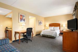日内瓦纽约州汉普顿日内瓦酒店的酒店客房配有一张床、一张书桌和一台电视。