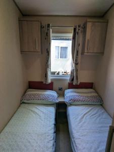 韦茅斯Littlesea Caravan on a Fabulous elevated position Haven Weymouth的小房间设有两张床和窗户