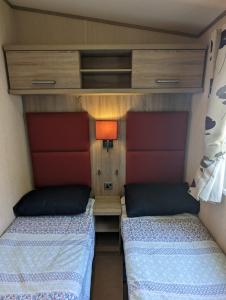 韦茅斯Littlesea Caravan on a Fabulous elevated position Haven Weymouth的小房间设有两张床和一盏灯