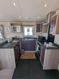 韦茅斯Littlesea Caravan on a Fabulous elevated position Haven Weymouth的小厨房配有紫色橱柜和炉灶