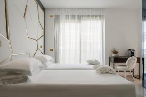 里乔内The Promenade Luxury Wellness Hotel的白色卧室设有两张床,配有窗户