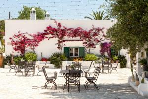 法萨诺Masseria San Nicola Savelletri - B&B的庭院配有桌椅和粉红色的鲜花