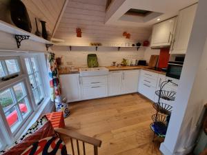 西莫林Square Oast Studio的厨房铺有木地板,配有白色橱柜。