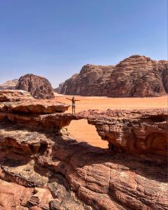 瓦迪拉姆Wadi rum Rozana camp的站在沙漠悬崖上的人