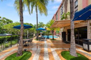 迈阿密迈阿​​密机场西汉普顿酒店的一个带桌椅的庭院,棕榈树