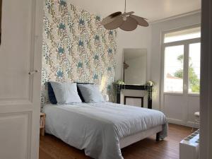 鲁瓦扬Appartement, Royan. Proche plage.的卧室配有白色床和花卉壁纸