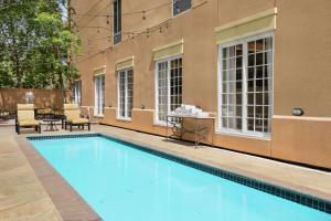 新奥尔良新奥尔良/圣查尔斯大道汉普顿酒店的一座带椅子和桌子的游泳池位于一座建筑旁边