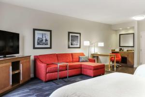 Heath希思希尔顿恒庭酒店的客厅配有红色沙发和电视
