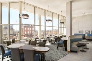 费城费城大学城惠庭套房酒店的餐厅设有桌椅和大窗户。