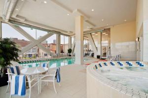 费城费城大学城惠庭套房酒店的一个带热水浴缸和桌椅的游泳池