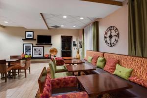 西米夫林汉普顿匹兹堡/西米夫林酒店的餐厅设有桌椅和墙上的时钟
