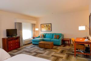里弗赛德滨江/科罗纳东汉普顿套房酒店的客厅配有蓝色的沙发和电视