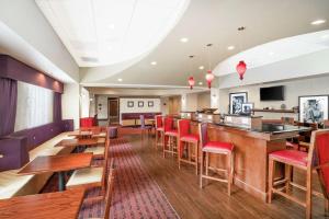 桑兹顿里士满机场希尔顿恒庭酒店的一间带酒吧和红色椅子的餐厅