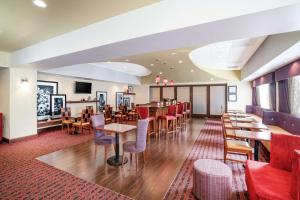 桑兹顿里士满机场希尔顿恒庭酒店的一间带桌椅的餐厅和一间酒吧