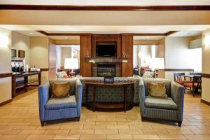 佛森福尔瑟姆希尔顿恒庭旅馆&套房酒店的客厅配有椅子和一张桌子及壁炉