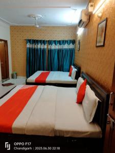 钱德加尔Hotel Diamond Ring Chandigarh的两张位于酒店客房的床,配有蓝色窗帘