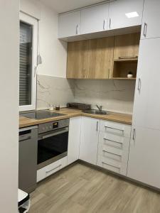 尼克希奇Apartman Oaza的厨房配有白色橱柜和水槽