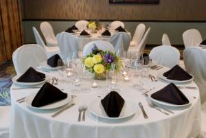 莱瑟姆阿尔巴尼机场希尔顿花园酒店的一张桌子,用来举办婚礼,上面有白色的桌子和椅子