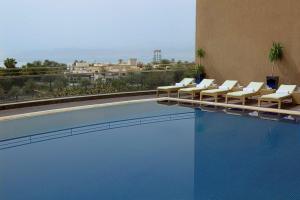亚喀巴亚喀巴希尔顿逸林酒店的酒店游泳池旁设有躺椅