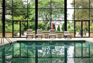 米尔福德DoubleTree by Hilton Boston-Milford的一个带椅子和大窗户的游泳池