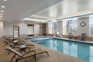 波士顿波士顿-剑桥希尔顿逸林酒店的一个带椅子和时钟的大型游泳池