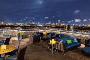 波士顿波士顿-剑桥希尔顿逸林酒店的一个带桌椅的屋顶露台,享有城市天际线