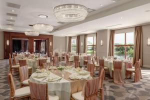 波士顿波士顿-剑桥希尔顿逸林酒店的宴会厅配有桌椅和吊灯。