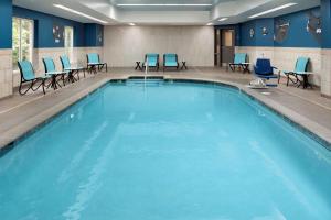 穆尔斯维尔摩尔斯维尔/夏洛特希尔顿花园酒店的一个带蓝色桌椅的大型游泳池