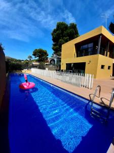 NáqueraExperience Valencia Bnb - Luxury Apartment Naquera Chalet 298 con Piscina的一座房子前面的游泳池,上面有红色的浮动