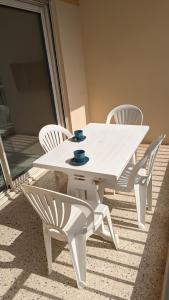 勒拉旺杜Studio avec coin nuit 150m de la plage的庭院里的白色桌椅