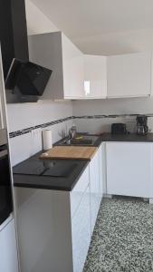 勒拉旺杜Studio avec coin nuit 150m de la plage的厨房配有白色橱柜和黑色台面