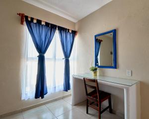 圣帕特里西奥梅拉克Bungalows Las Hamacas的客房设有带蓝色窗帘和镜子的窗户。