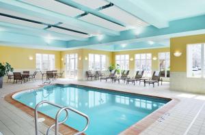 尚佩恩尚佩恩/厄巴纳希尔顿花园酒店的一个带桌椅的房间的游泳池