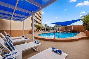 达尔文达尔文希尔顿酒店的酒店游泳池设有椅子和蓝伞