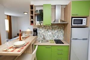 苏托莫雷奥克托普斯公寓的厨房配有绿色橱柜和白色冰箱