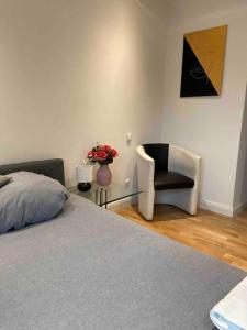 陶努斯山麓霍夫海姆Luxury apartment with air conditioning & Jaccuzzi near Frankfurt Wiesbaden的一间卧室配有一张床、一把椅子和花瓶