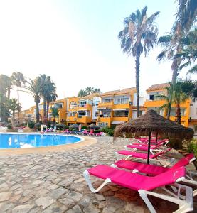 滨海罗克塔斯Apartamento Los Mangos的游泳池旁一排带遮阳伞的躺椅