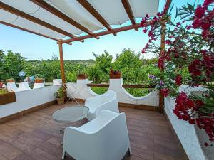 维耶斯泰Il Giunco B&B的阳台配有白色的椅子、桌子和鲜花