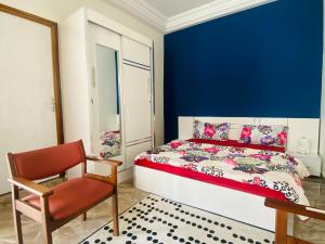 达喀尔RESIDENCE EL HADJI的一间卧室设有蓝色的墙壁、一张床和一把椅子
