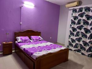 瓦加杜古Ouedraogo Property Management的一间卧室设有紫色的墙壁和一张紫色床单